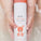 The image features a bottle of Tropic Little Joey Baby Washing Milk being held gently in water. The packaging is white with a playful orange kangaroo illustration, emphasizing its suitability for babies. Key ingredients, including rice milk, white tea, and kangaroo paw flower extract, are highlighted on the label. The product is Certified Organic and Pediatrician Tested, ensuring it is safe and gentle for delicate baby skin.